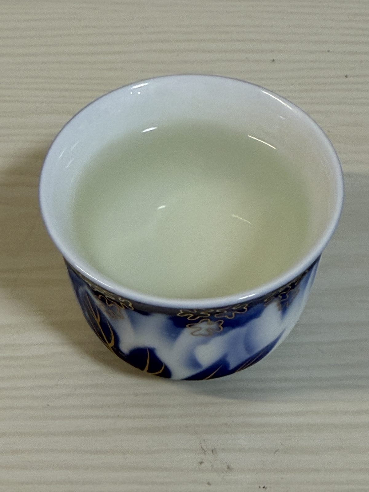 Pale sake seen against the white porcelain interior of the guinomi