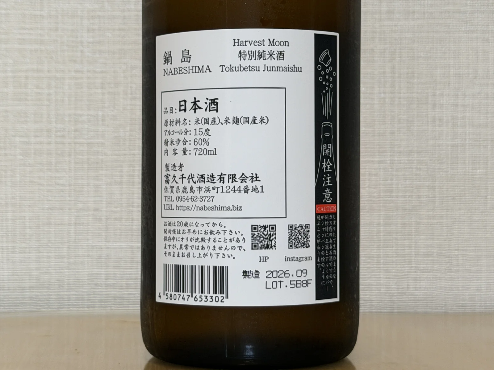 Back label of Nabeshima Harvest Moon showing tokubetsu junmai, 60 percent polishing ratio, 15 percent alcohol, and a caution panel about gas pressure