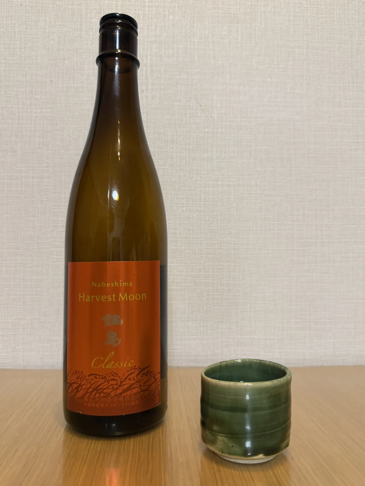 Nabeshima Harvest Moon Classic bottle with an orange label beside the Oribe ware guinomi