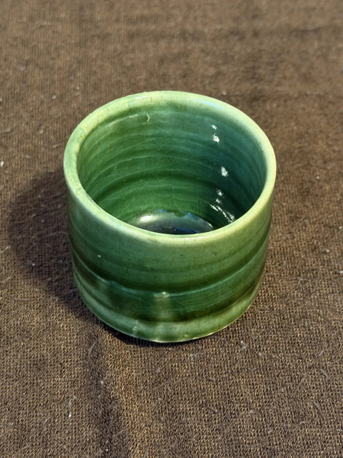Oribe ware guinomi in brighter light, showing its brighter green glaze and horizontal throwing lines