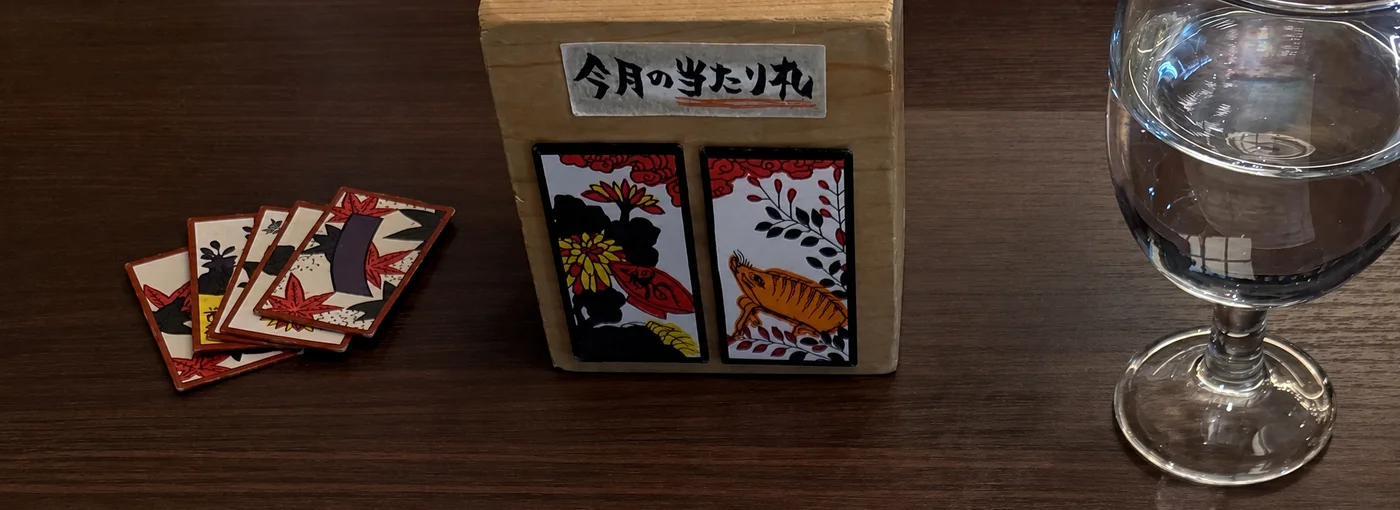 Hanafuda cards and a wooden card box at Sumiyoshi Shuhan, with a water glass for chasing sake