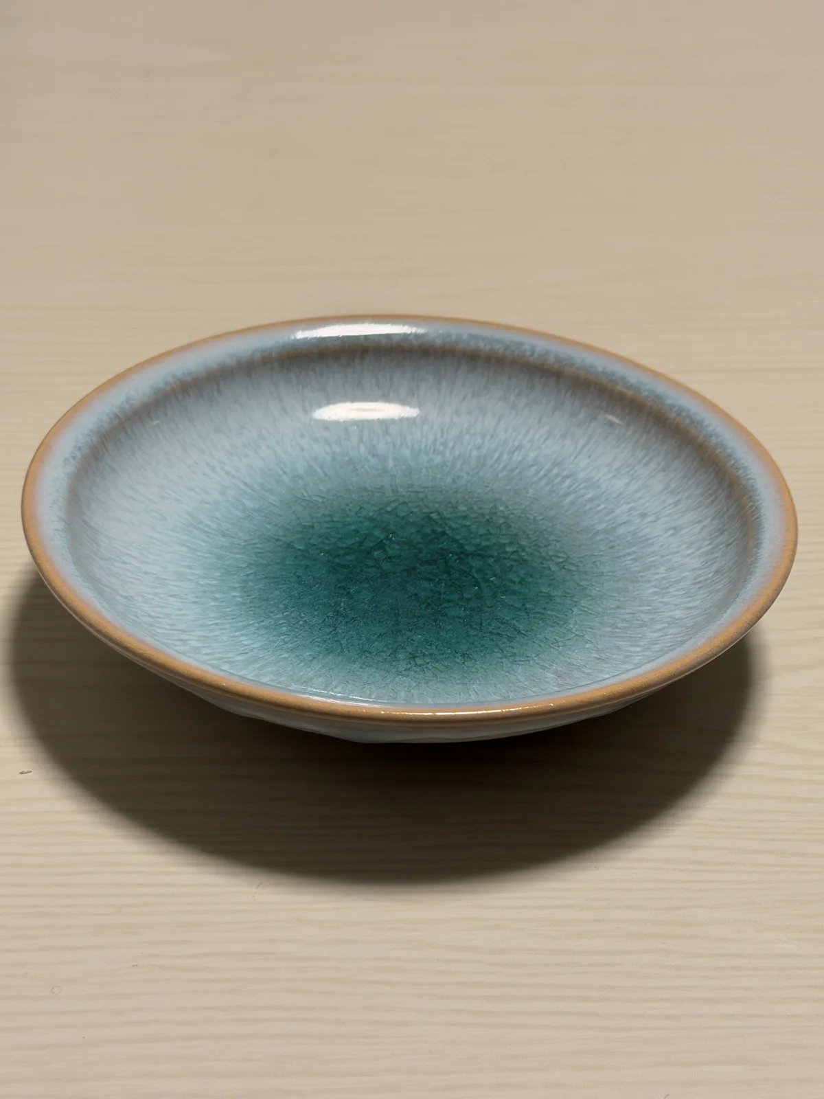 Empty Hagi ware plate seen at an angle, showing the turquoise center and fine crackle in the glaze